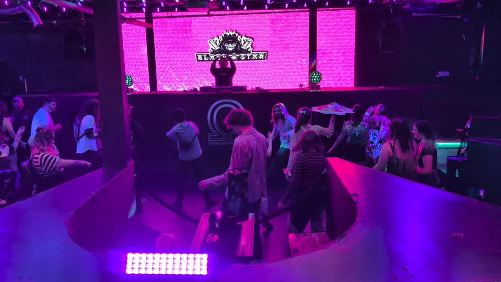 Seattle club dance floor with a magenta LED wall behind the DJ