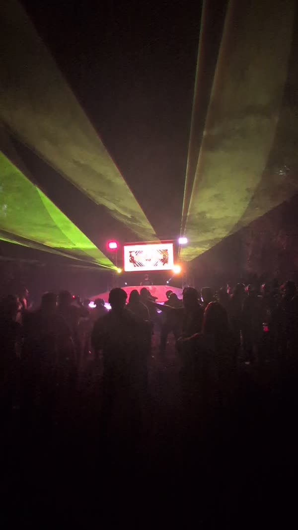 Green lasers fanning over an outdoor festival crowd at night