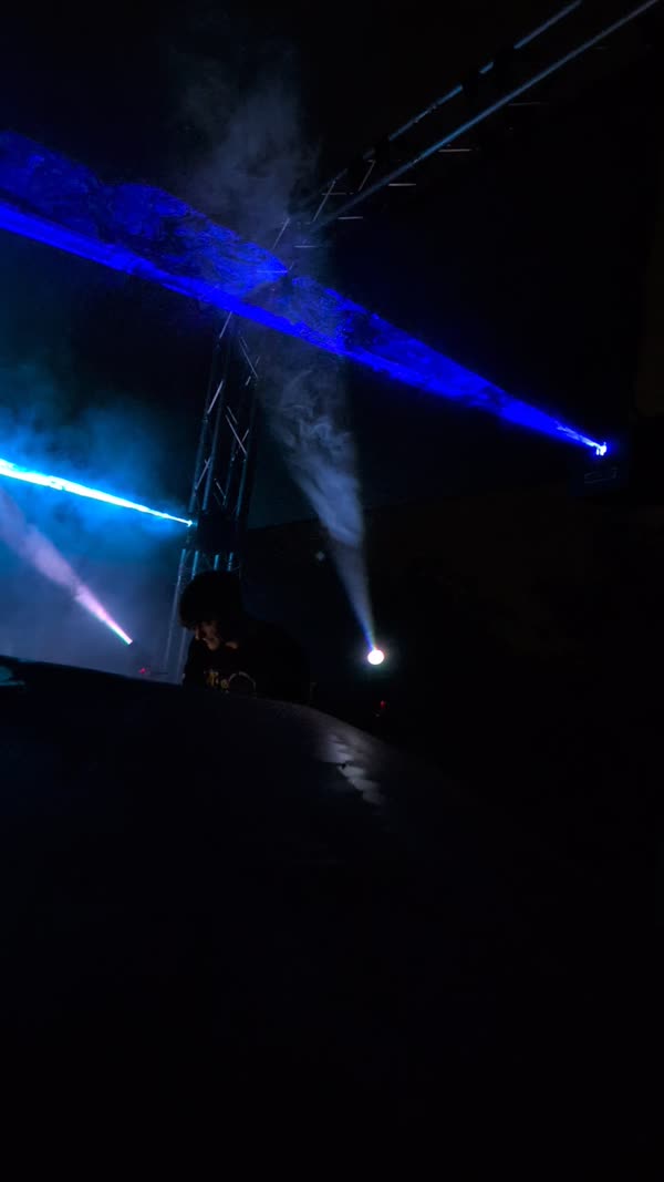 Blue light beams cutting through haze from a lighting truss
